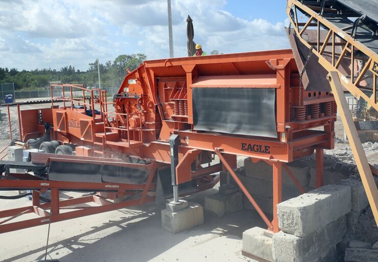 Discharge material feeds to a separate conveyor coming out of the side of the crusher at a 90-degree angle.
